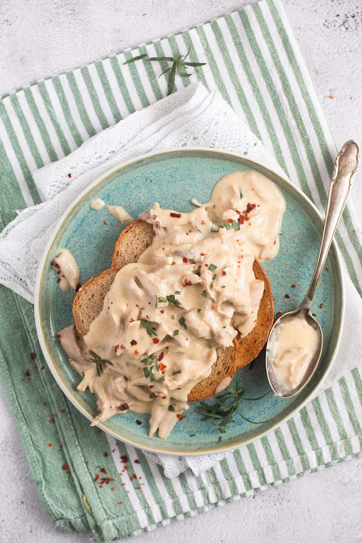 small plate with two slices of bread covered with creamed turkey and a spoon with extra sauce.