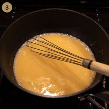 whisking sauce in a pan using a small wire whisk.