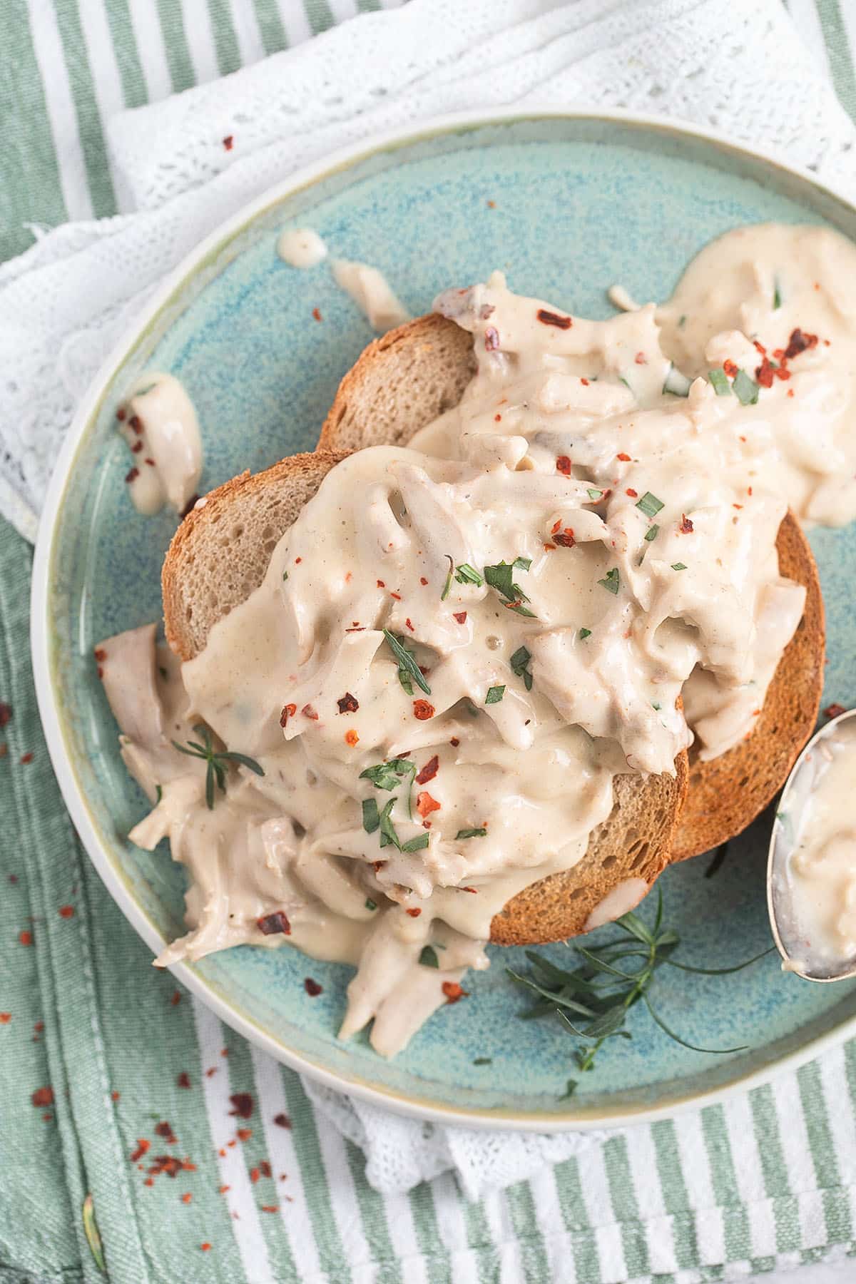 two toasts covered with creamy turkey sauce on a small blue plate.