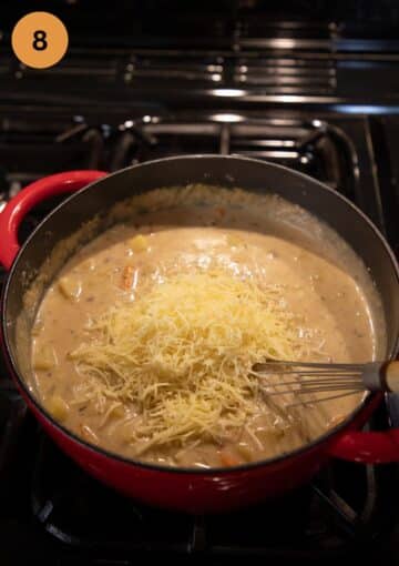 adding grated cheese to a pot of soup.