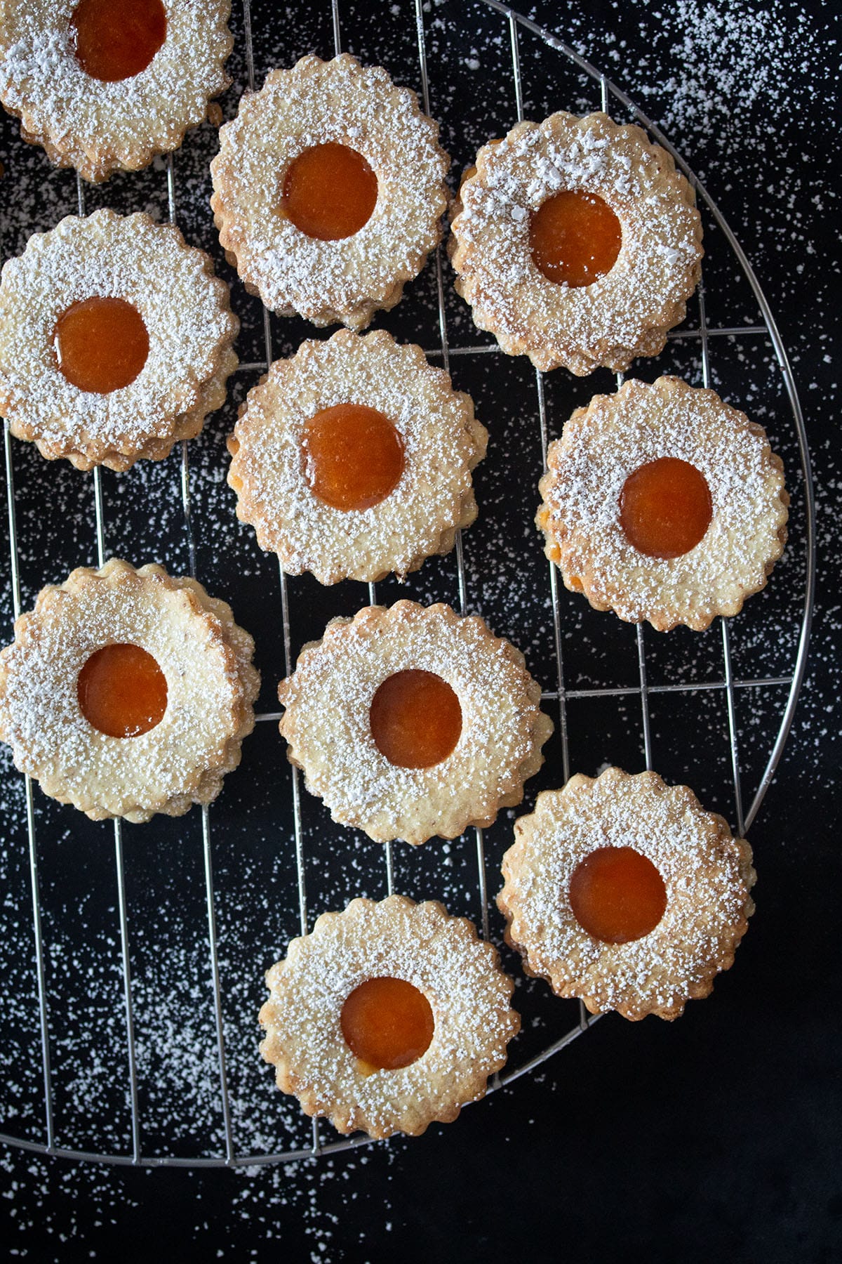 many apricot cookies on a cooling rack on a blackboard.