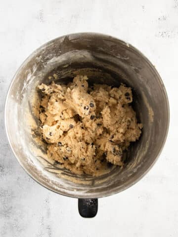 mixing chocolate chips in cookie dough in a bowl.