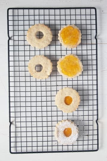 filling linzer style cookies with apricot jam.