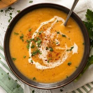 parsnip soup with carrots drizzled with cream in a bowl.