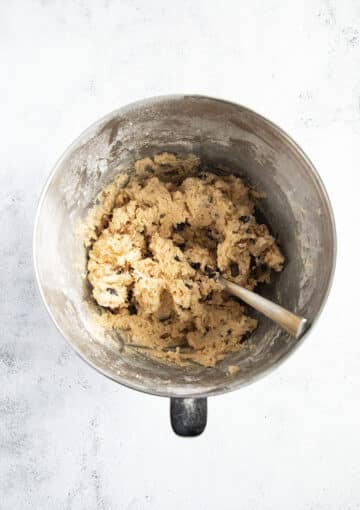folding pecans and chocolate chips into cookie batter with a spoon.