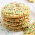 five sprinkles sugar cookies with jammies stapled on a plate, one halved.