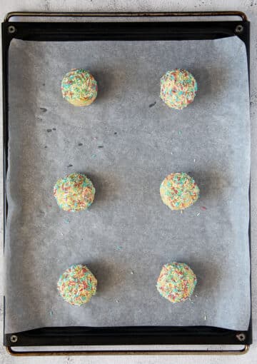 unbaked cookies with sprinkles on a baking sheet.