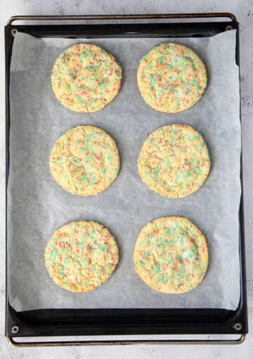 freshly baked sprinkle cookies resting on a baking tray.