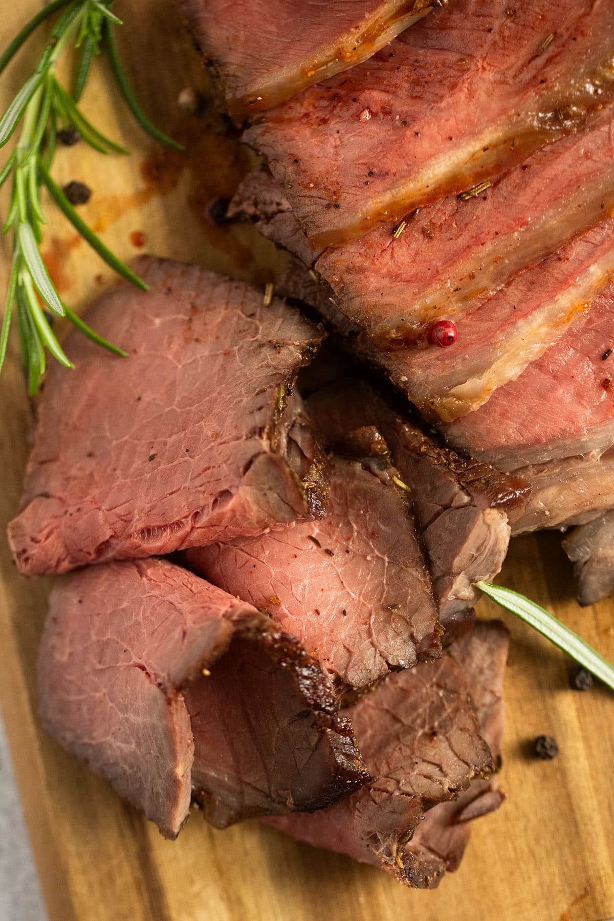 close up of sliced pieces of roast beef on a cutting board.