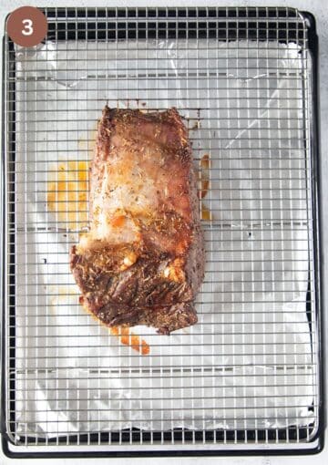 a roasted piece of beef resting on a wire rack.