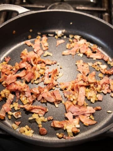 frying bacon and onions in a pan.