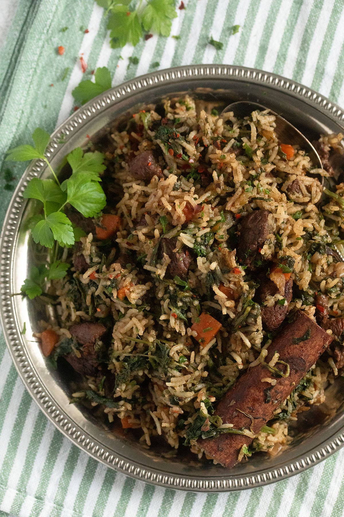 a dish with lebanese rice and lamb with a cinnamon stick on top.