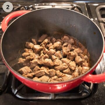 browning lamb pieces in a pot on the stove top.