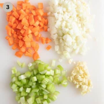 chopped carrots, onions, celery, and garlic on a cutting board.