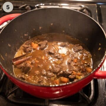 adding stock and rice to a lamb dish in a large pot.