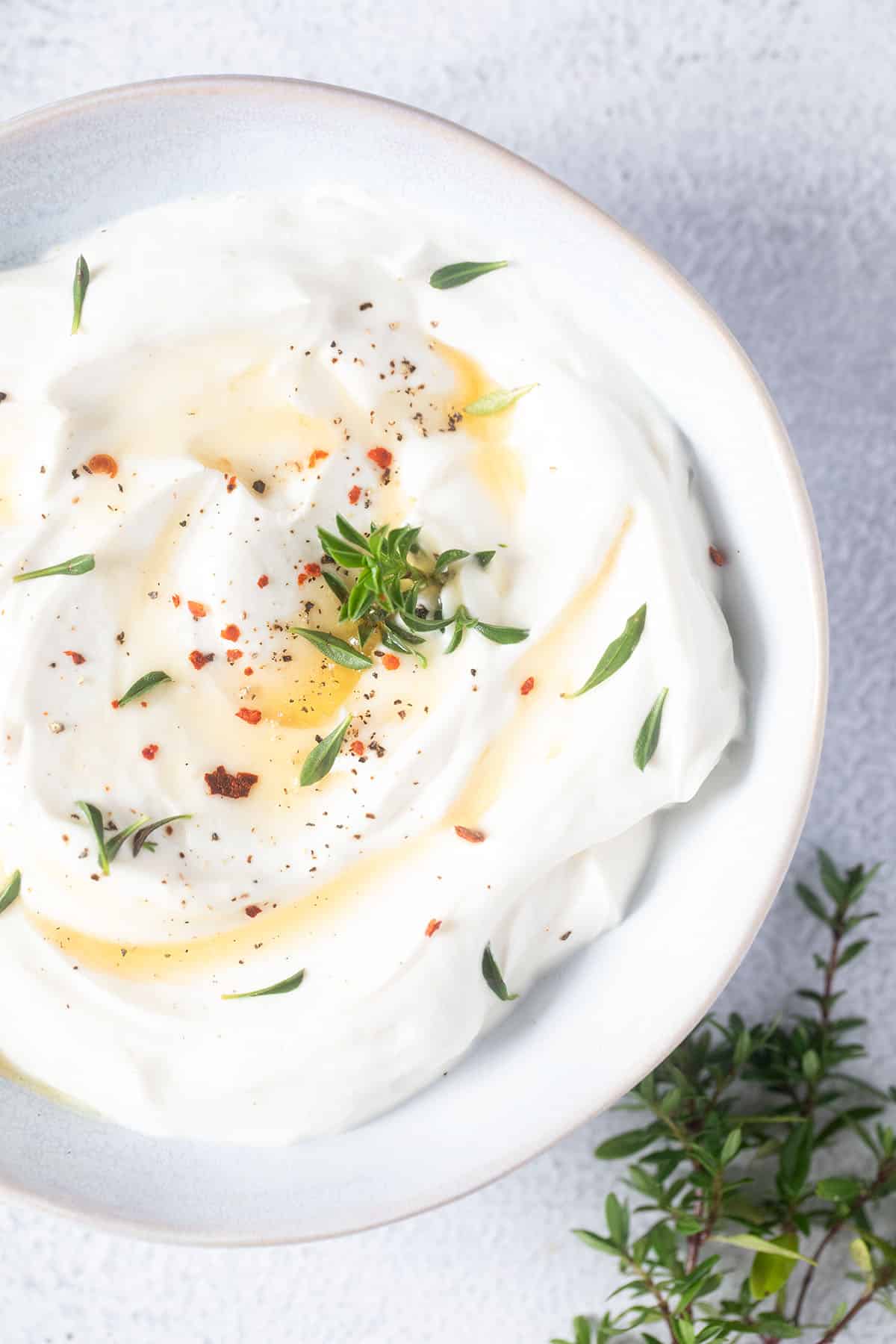 bowl with fluffy and creamy ricotta and thyme sprigs beside it.