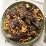 chicken livers served with sauteed onions on a green plate.