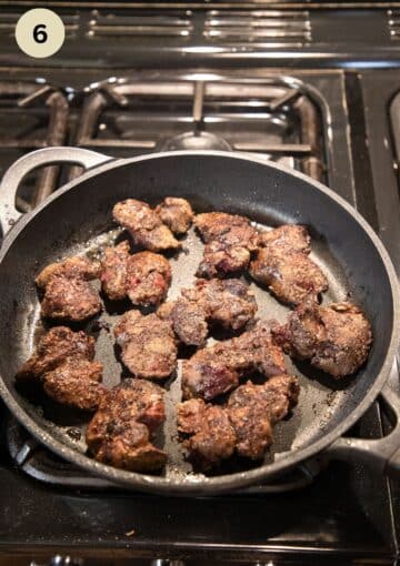 chicken livers frying in a nonstick pan on the stove top.