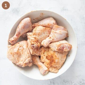seasoning chicken thighs and drumsticks in a large bowl.