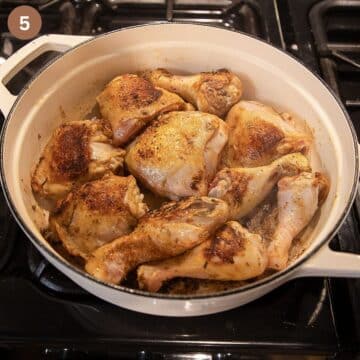 browning chicken thighs and drumsticks in a white dutch oven.