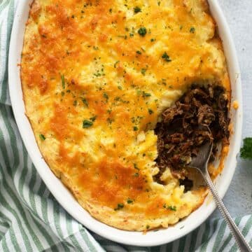 leftover lamb shepherd's pie with cheesy mashed potatoes in an ovenproof dish showing the filling.