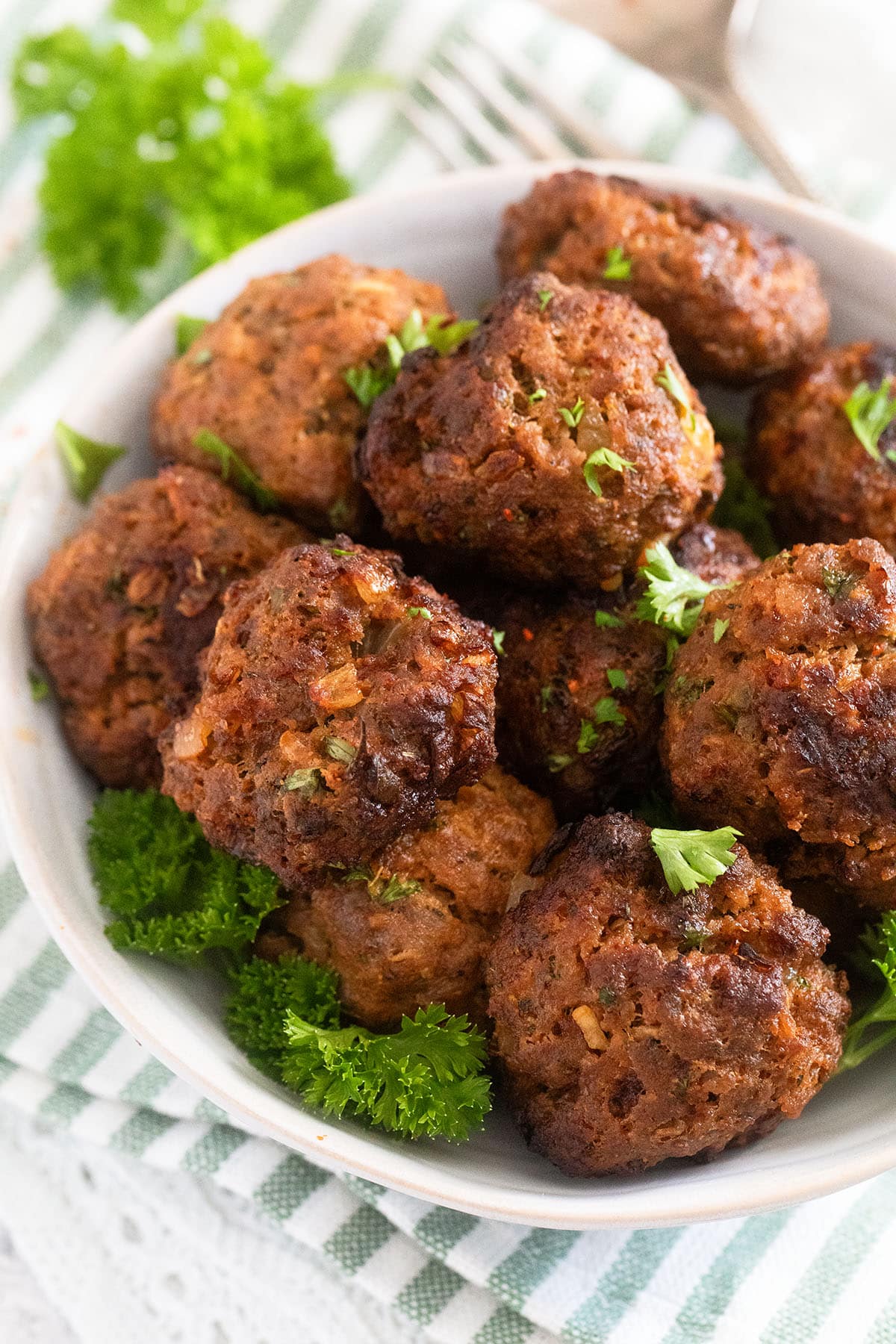 many round meatballs made without eggs in a bowl on a striped kitchen cloth.