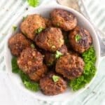 many small meatballs without eggs in a bowl with fresh parsley around them.