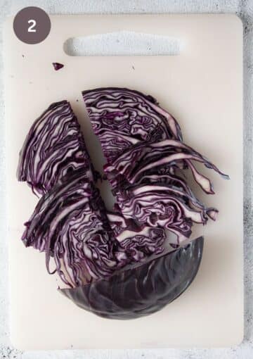 cutting red cabbage slices in half on a cutting board.