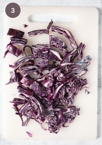 shredded red cabbage on a cutting board.