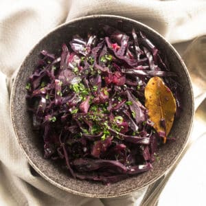 slow cooker red cabbage and a bay leaf served in a rustic bowl.