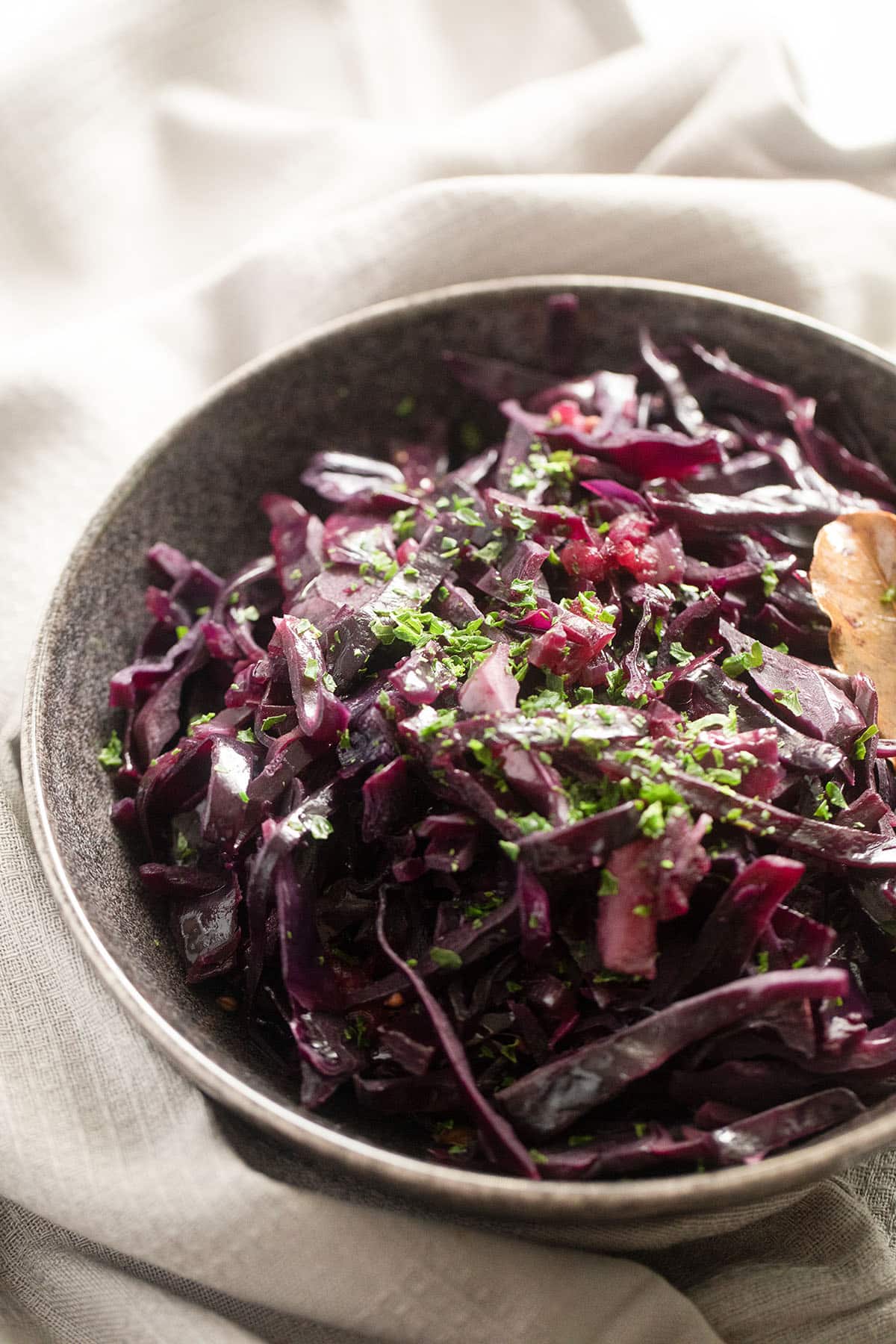 crock pot red cabbage in a bowl sprinkled with fresh parsley.