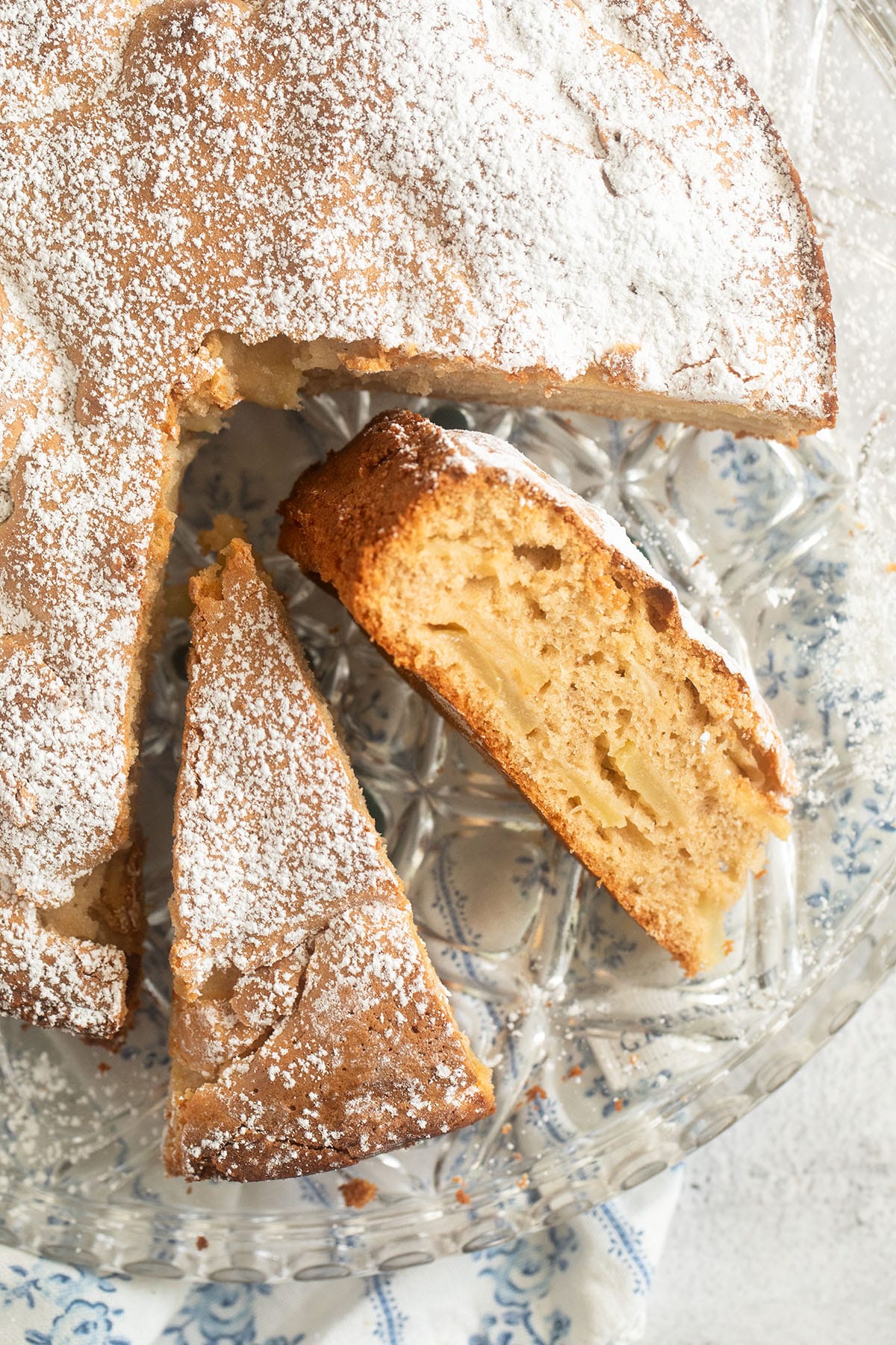 sliced apple cake made with olive oil and cinnamon on a cake platter.