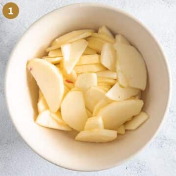 thin apple slices mixed with lemon juice and sugar in a bowl. 