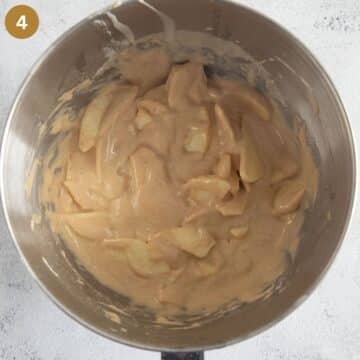 adding apple slices to cake batter in a bowl.