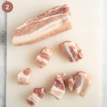 cutting raw pork belly on a cutting board.