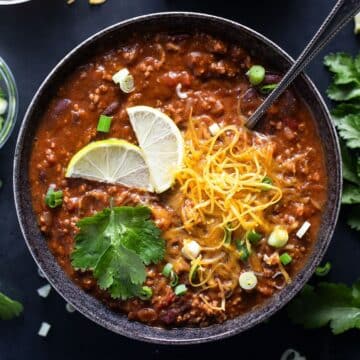 refried bean chili topped with cilantro, melted cheese and lime wedges.
