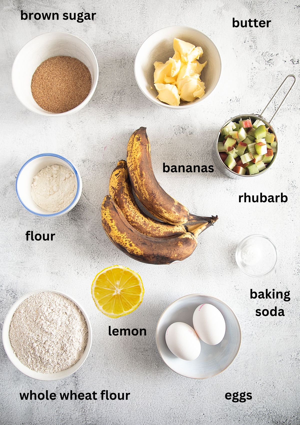 labeled ingredients for making banana bread with rhubarb arranged on the table.