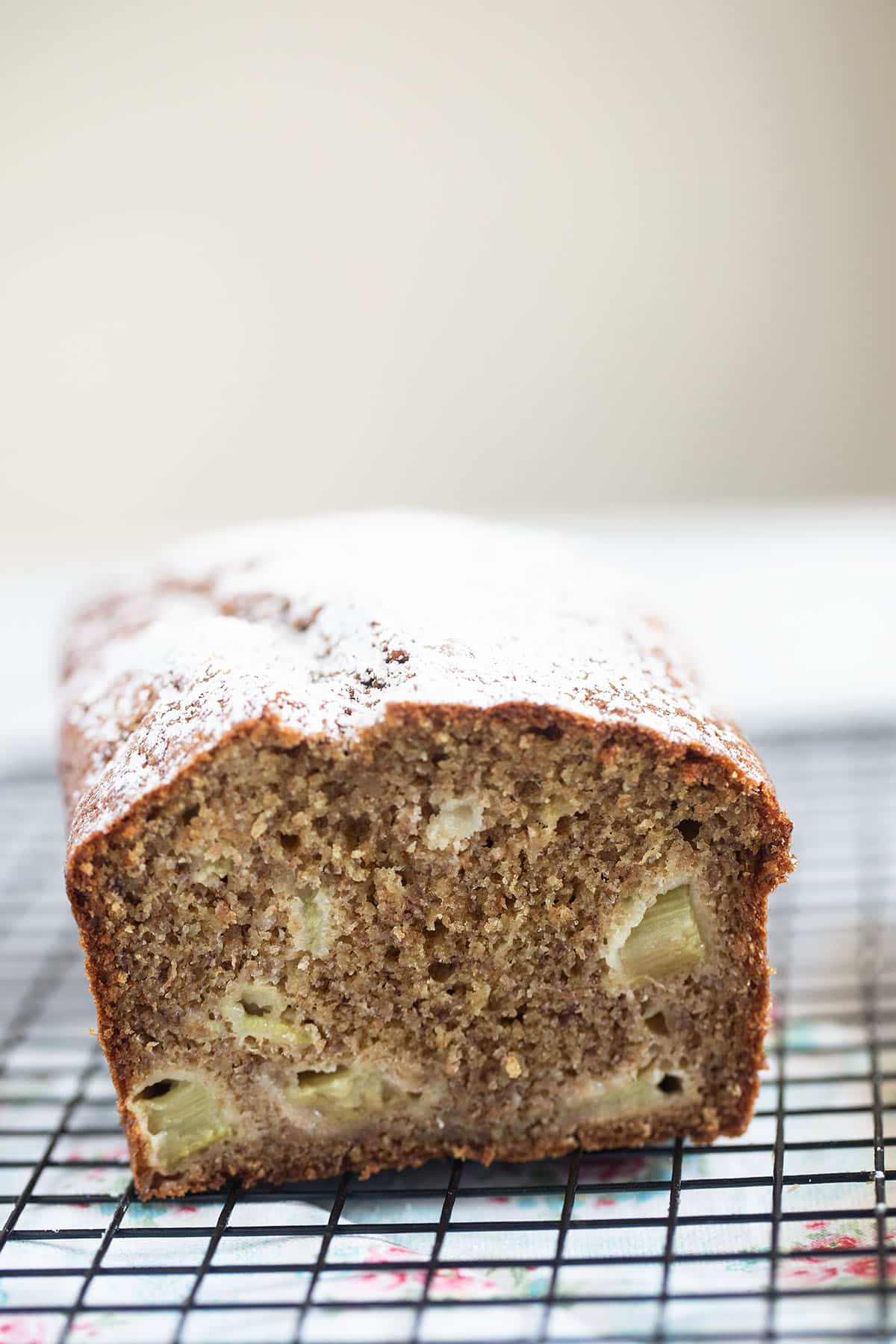 banana rhubarb bread cut to show the inside crumb and sprinkled with icing sugar.