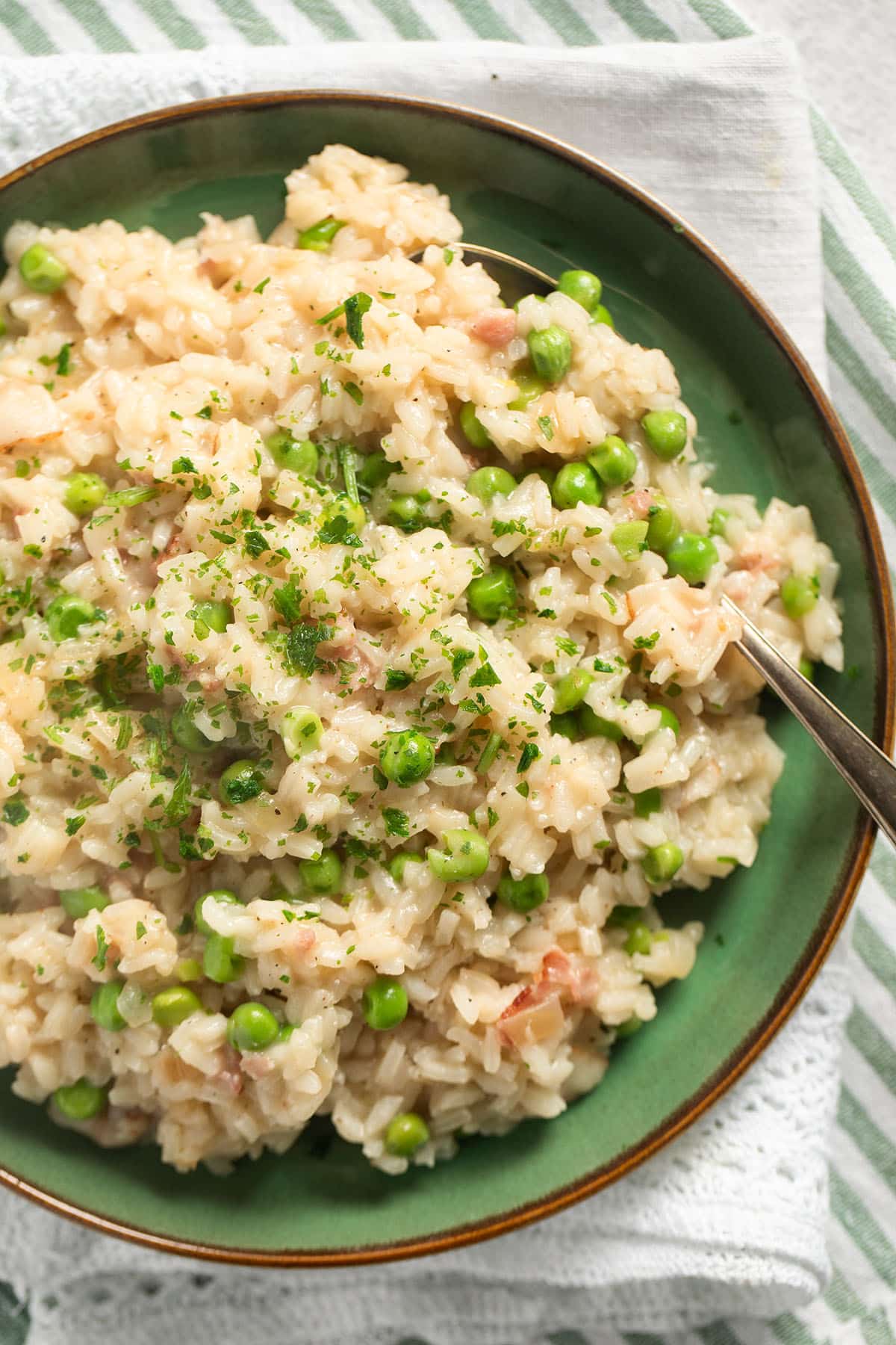 pea and bacon risotto sprinkled with parsley on a plate.