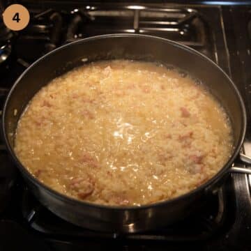 adding stock to risotto in a large pan.