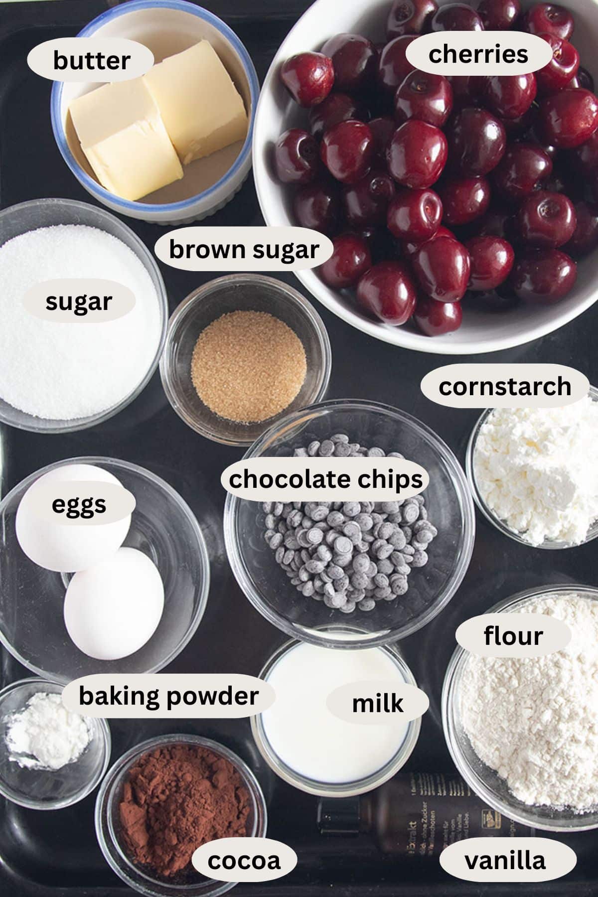 labeled ingredients in bowls for making cherry muffins with chocolate chips and cocoa.
