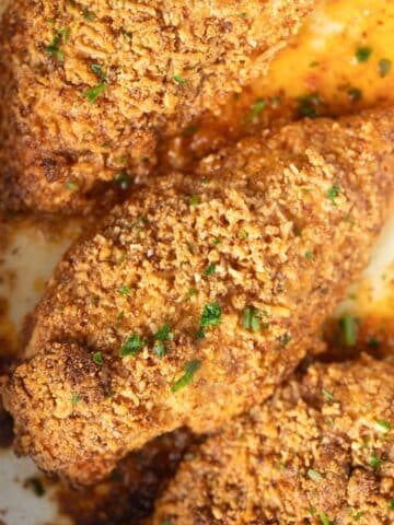 almond crusted chicken breast pieces golden brown and sprinkled with parsley.