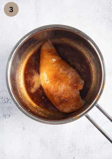 one chicken breast dipped in a butter and spices mixture in a small saucepan.