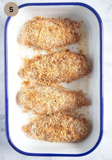 four chicken breasts coated with almonds in a baking tin before baking.