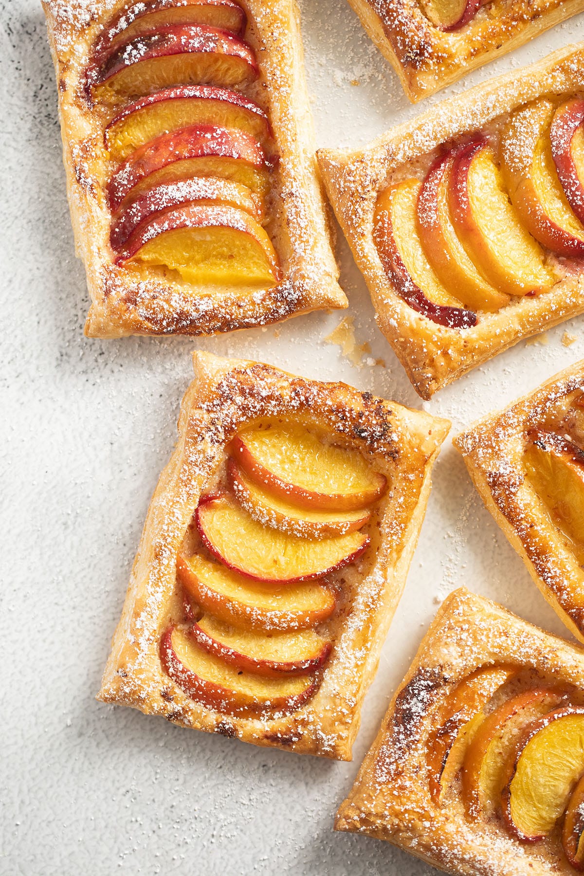 several mini tarts with puff pastry and peach slices.