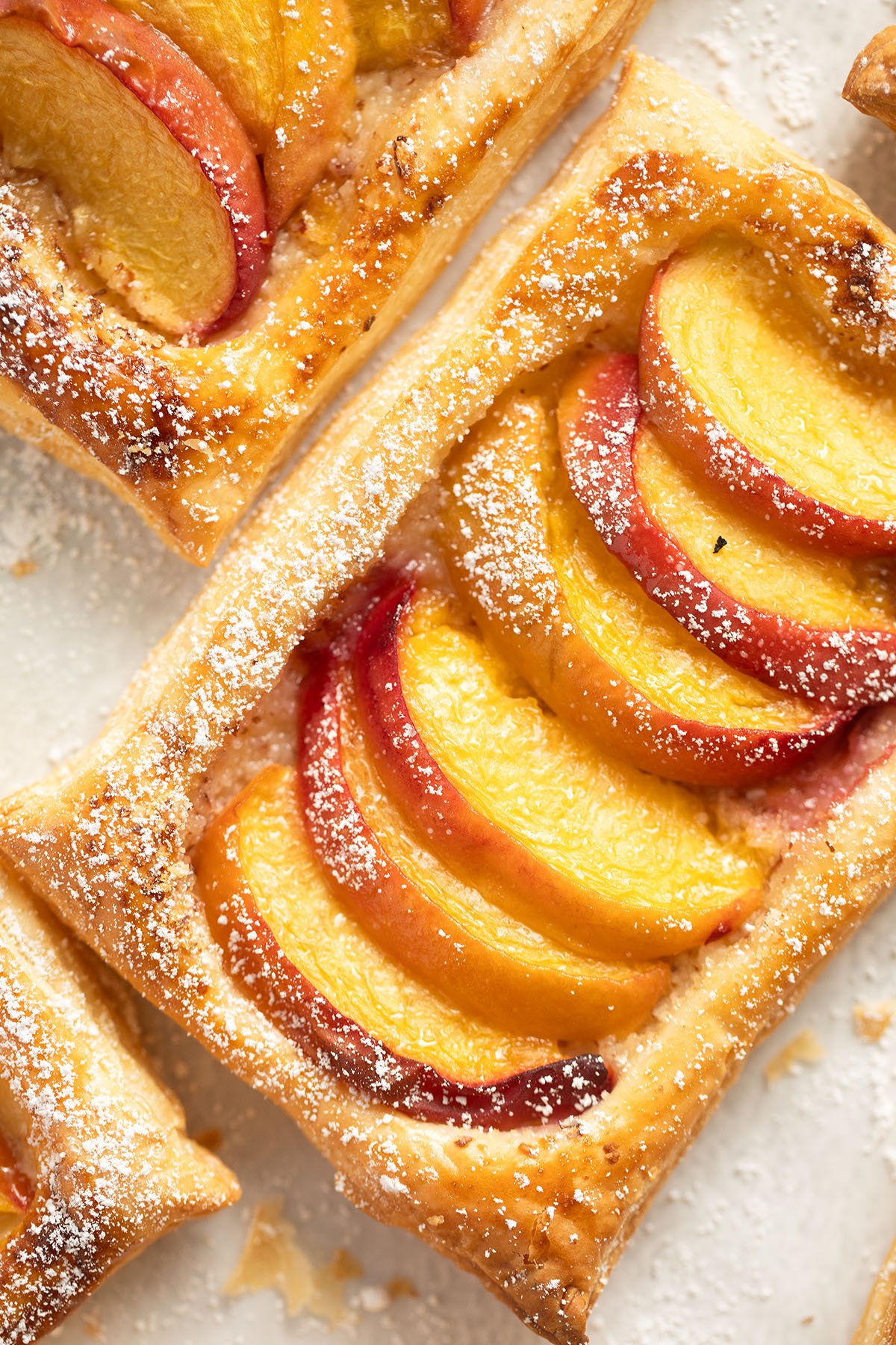 one rectangular puff pastry tart with sliced peaches on top.