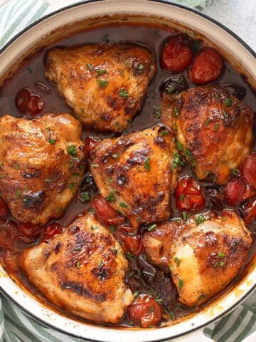 honey harissa chicken thighs with cherry tomatoes in a large dutch oven.