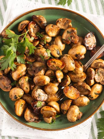 spanish mushroom tapas sprinkled with parsley on a small plate.