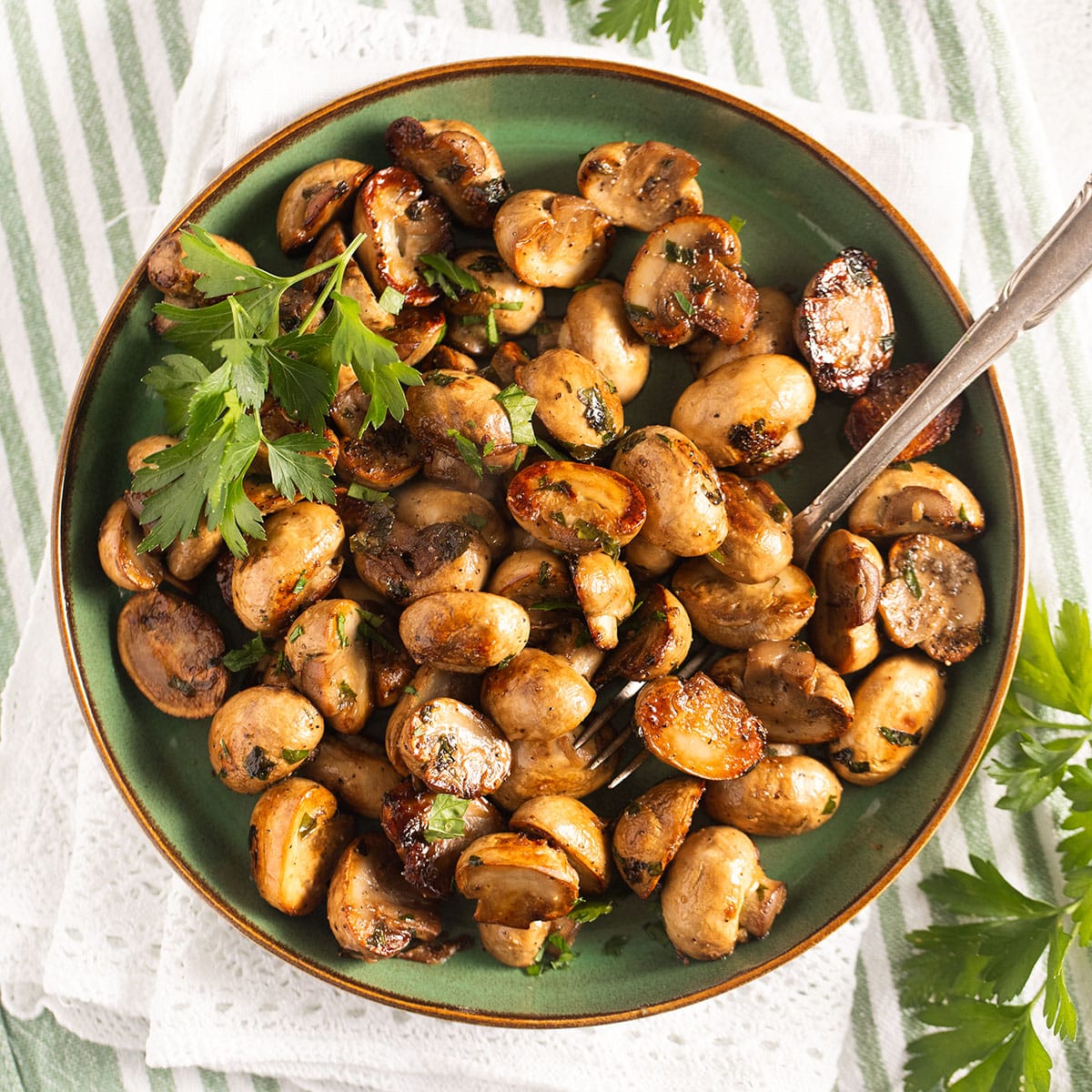 spanish mushroom tapas sprinkled with parsley on a small plate.