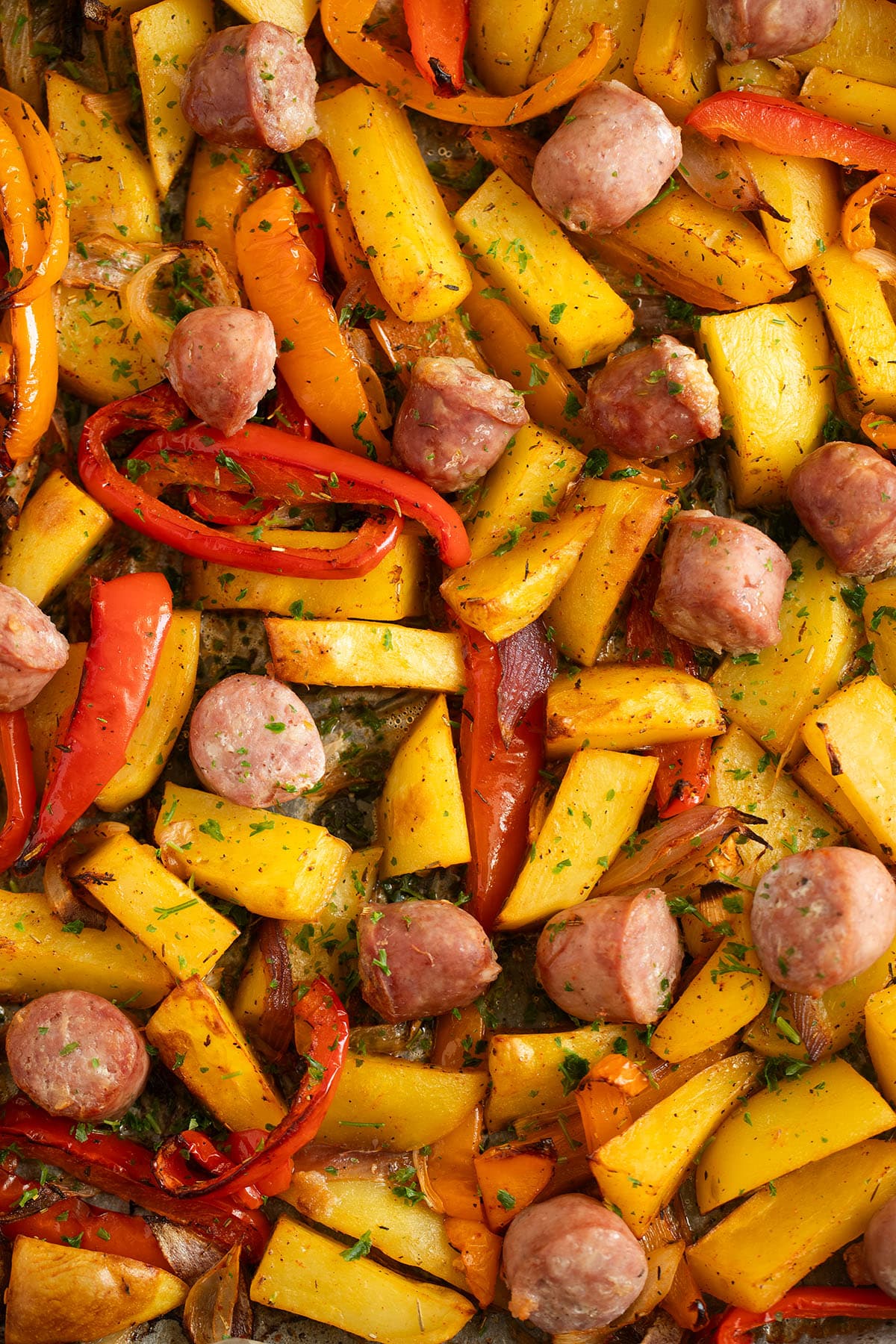 baking sheet full of roasted potatoes, vegetables and sausage pieces.